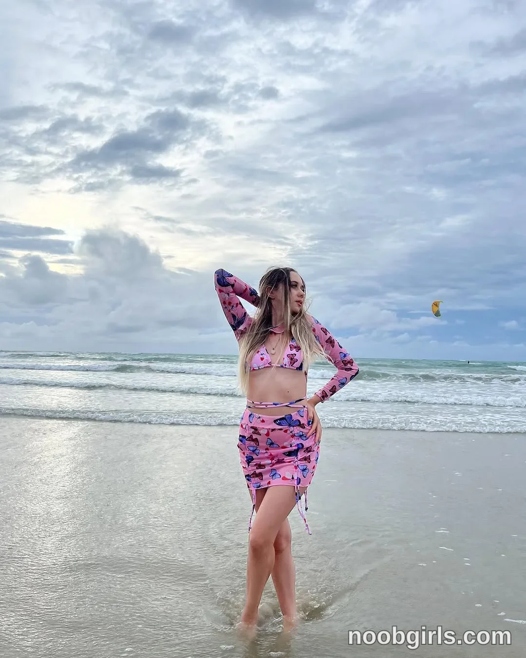 Elina standing in shallow ocean water at the shore with feet crossed