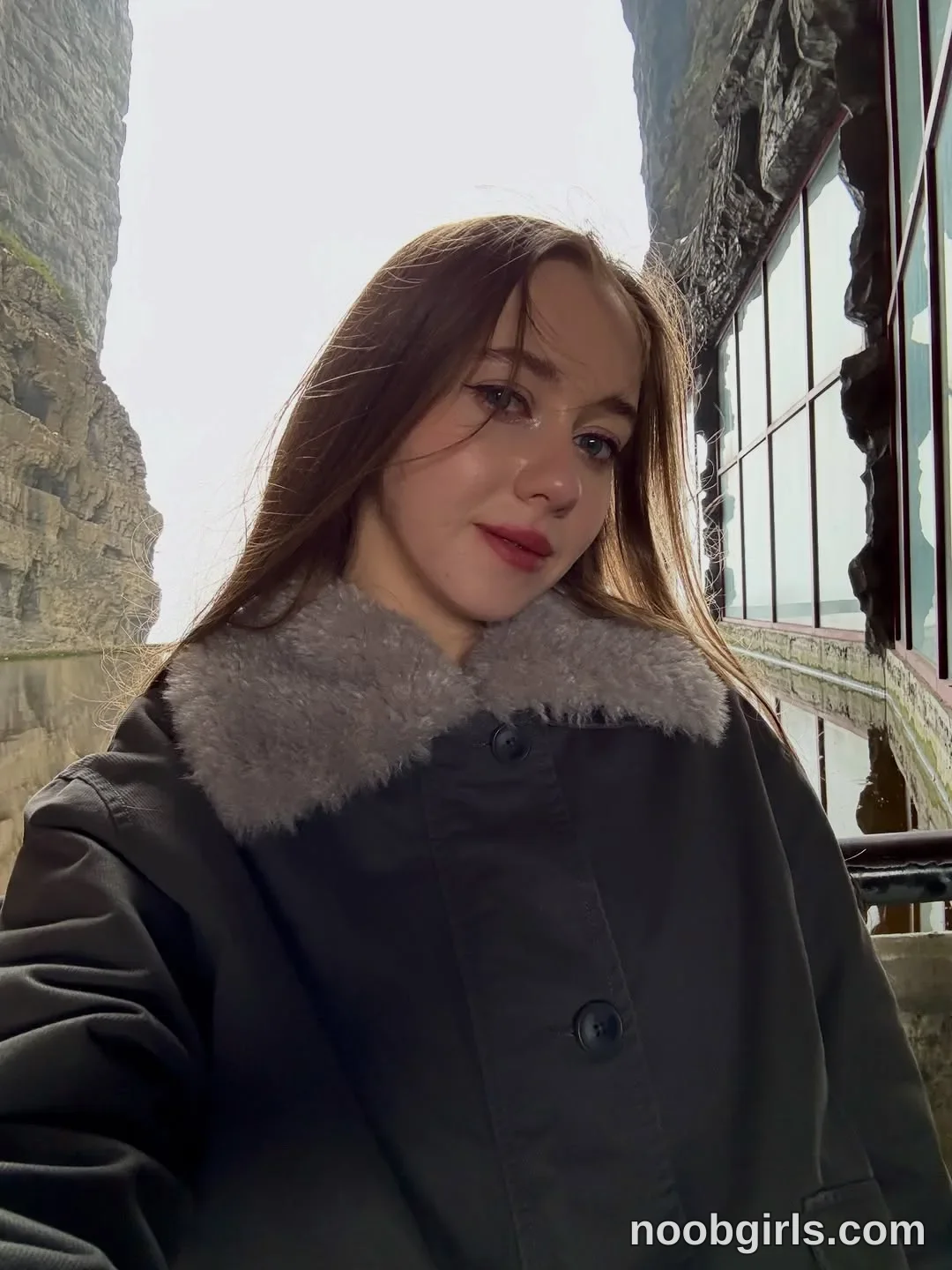 Elina looking directly at the camera wearing dark grey jacket with a grey faux-fur collar