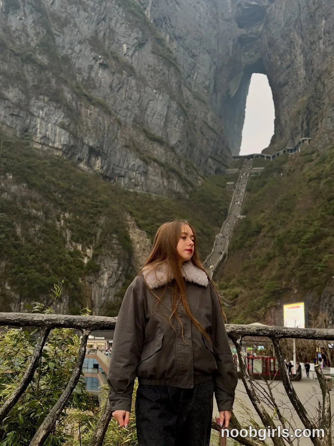 Elina standing outdoors in three-quarters profile looking to the right wearing dark grey jacket with light grey fur collar