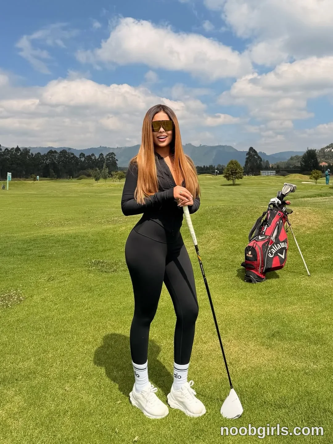 sary_hott standing on grass wearing black long-sleeve zip-up top in golf course