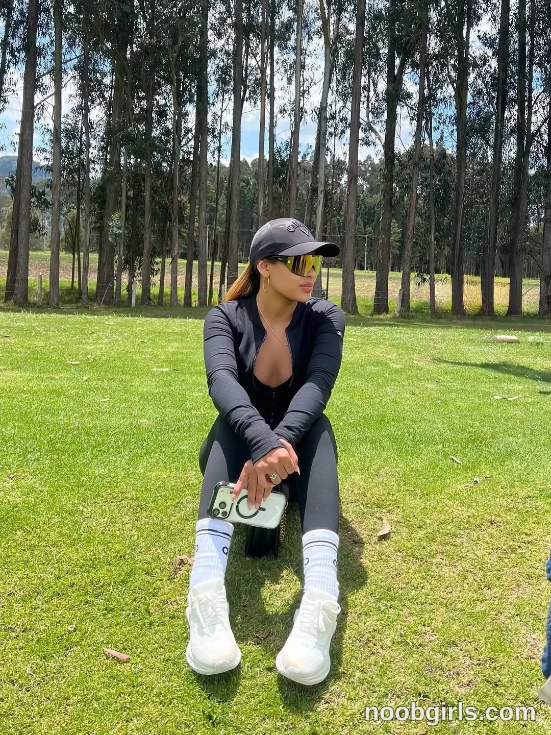 sary_hott sitting on the grass with hands clasped around a phone