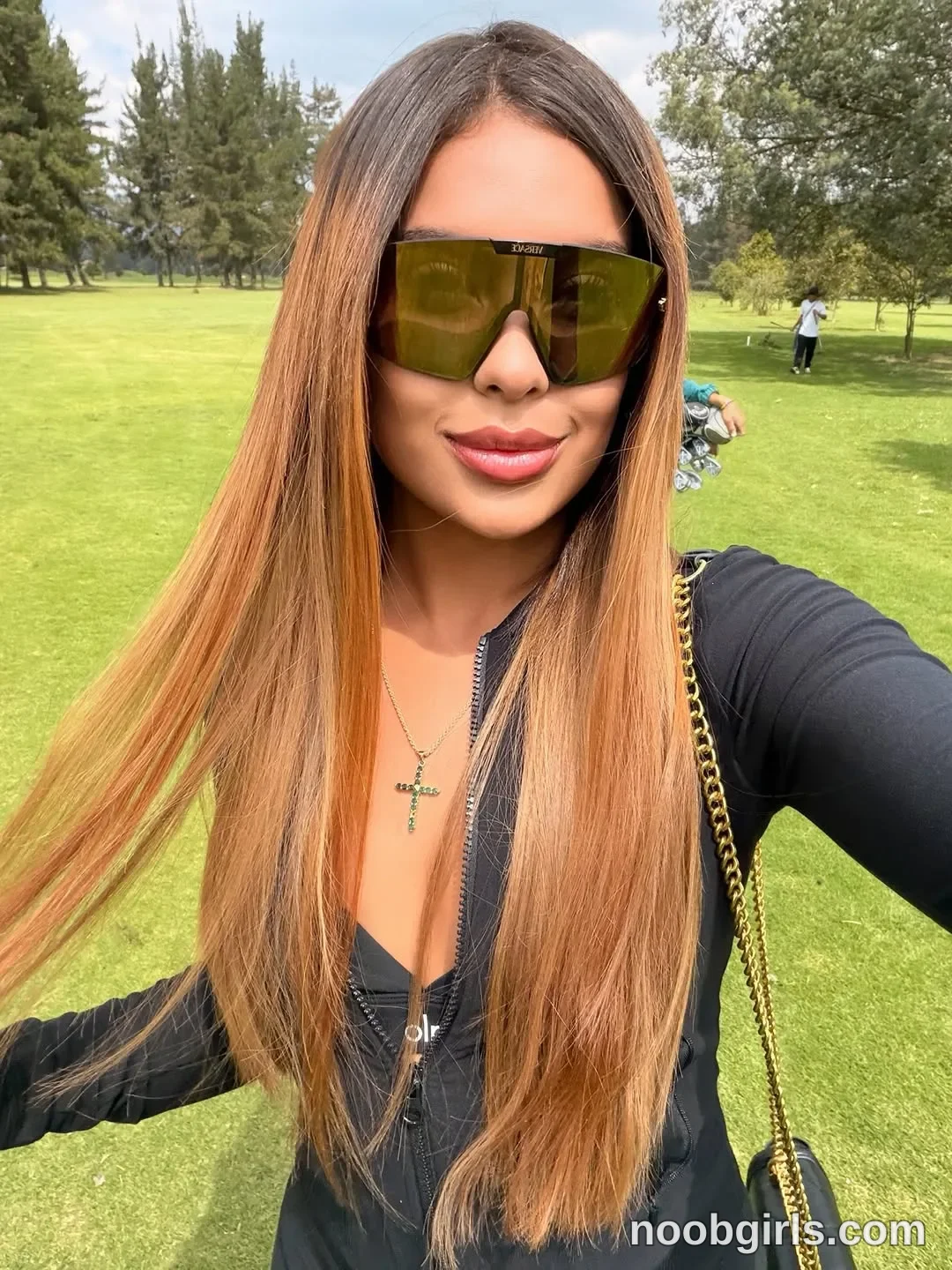 sary_hott standing outdoors taking a selfie wearing black long-sleeve zip-up top or jumpsuit in golf course