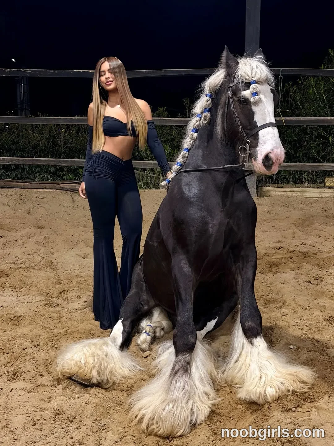 sary_hott standing next to a horse that is sitting down on the sand wearing black off-the-shoulder long-sleeve crop top