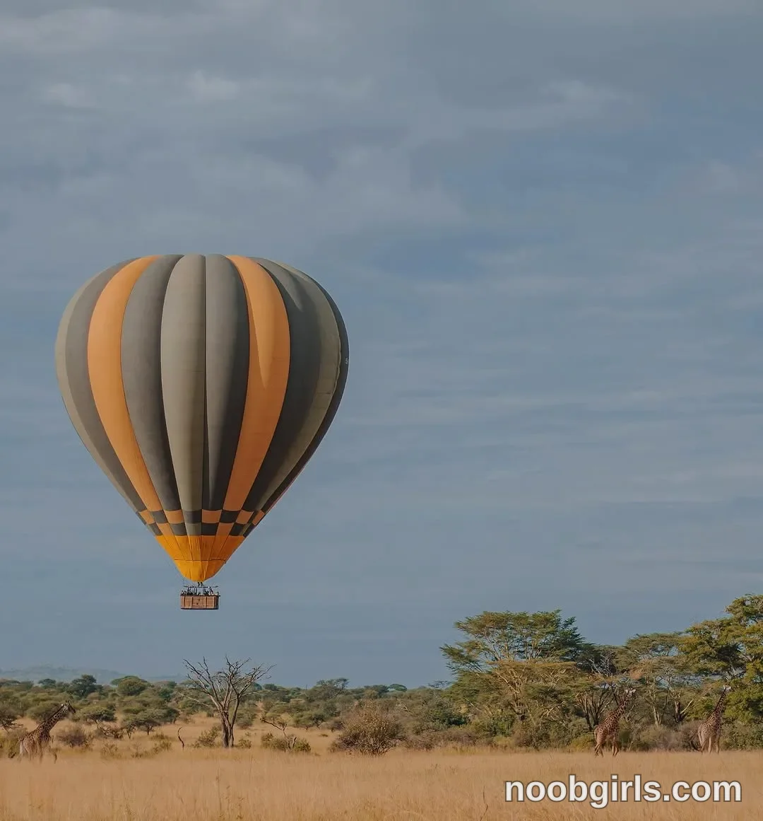 TAANNI No identifiable woman is visible. A hot-air balloon is airborne above the grassland in dry grassland