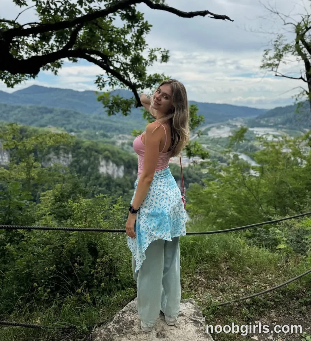 tastypoint standing on a rock wearing pink spaghetti strap tank top in mountain overlook