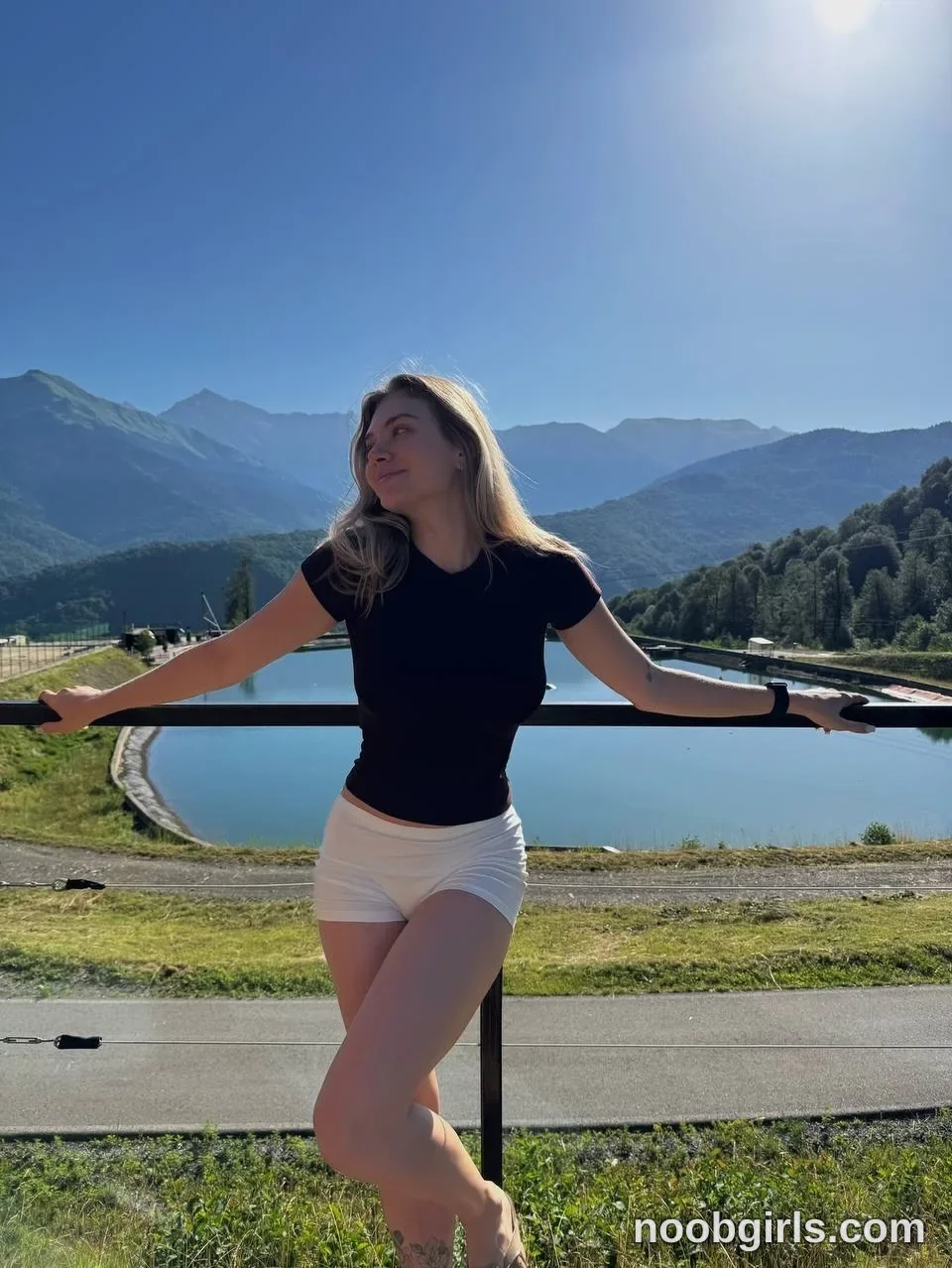 tastypoint leaning back against a metal railing with arms outstretched wearing black short-sleeved t-shirt