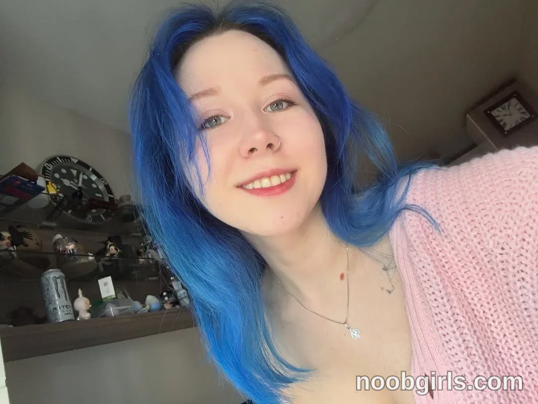 theblue_moonie smiling towards the camera wearing light pink knitted cardigan in residential room