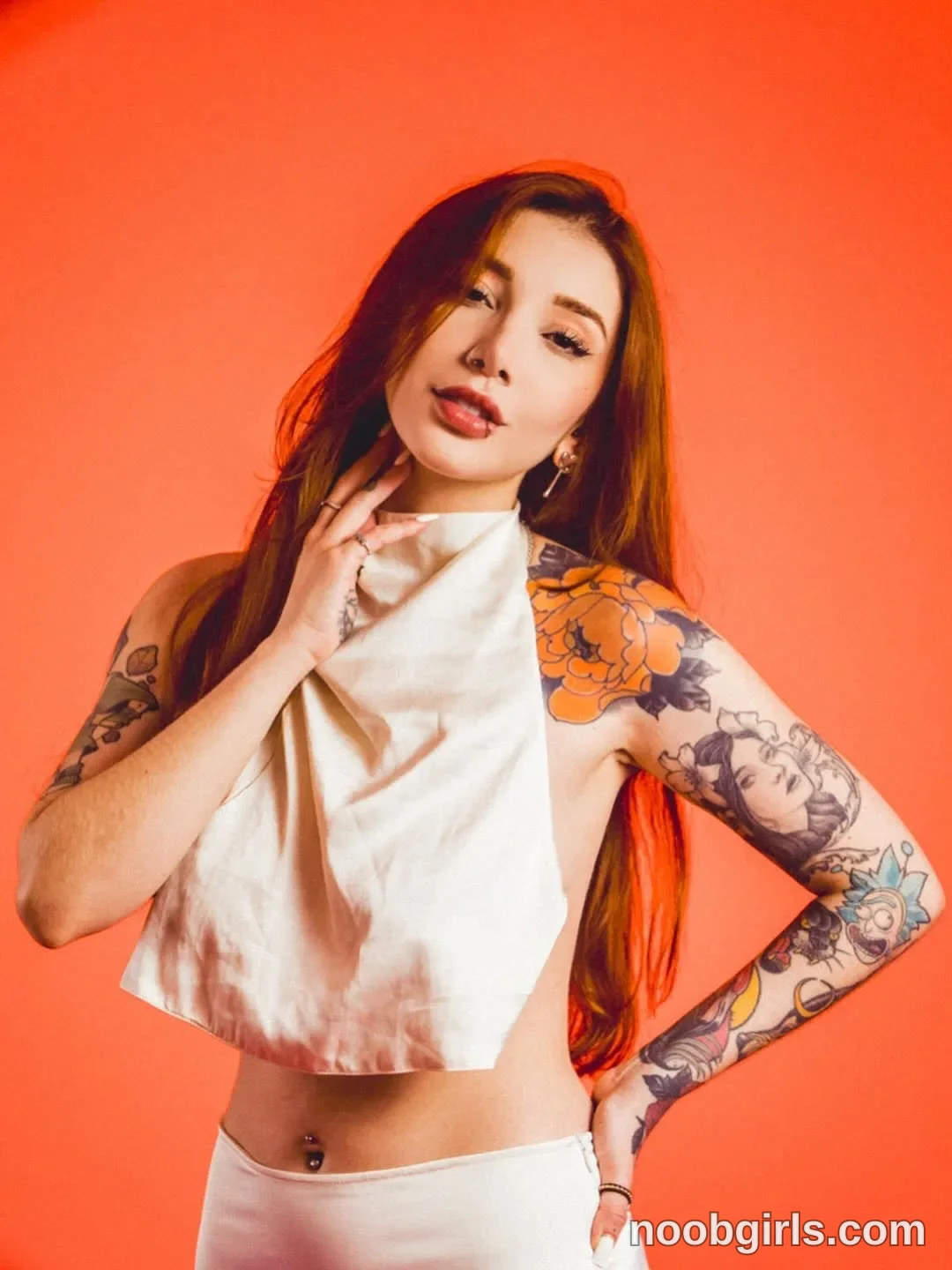 Alicia Standing with one hand touching the side of her neck wearing White sleeveless halter-style crop top