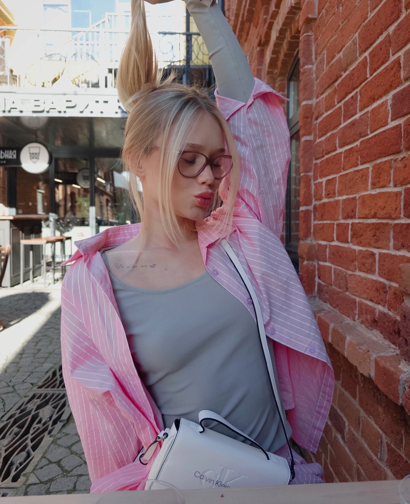 tollysage holding up her hair wearing pink striped shirt in urban street