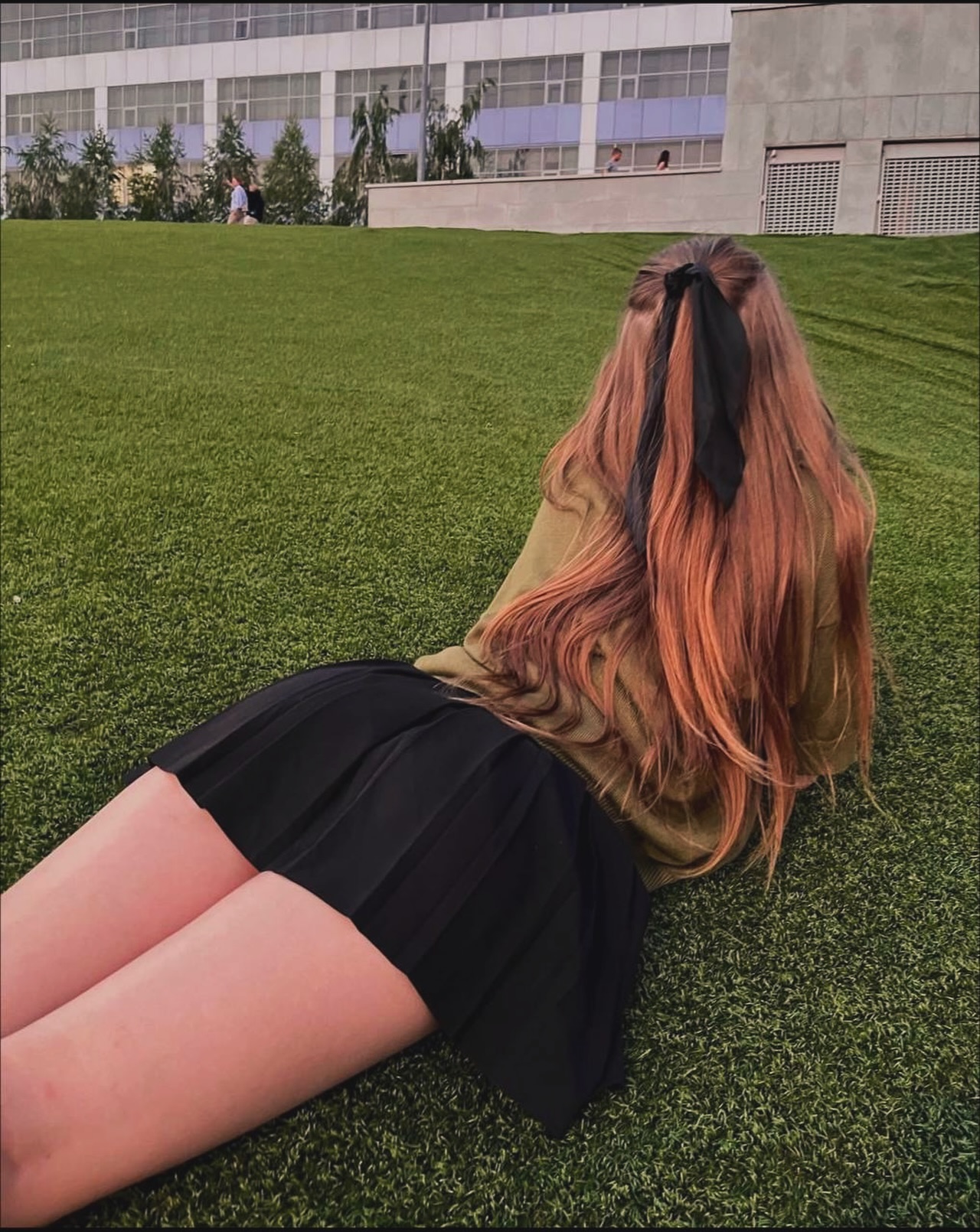 tollysage lying on grass wearing olive sweater in lawn