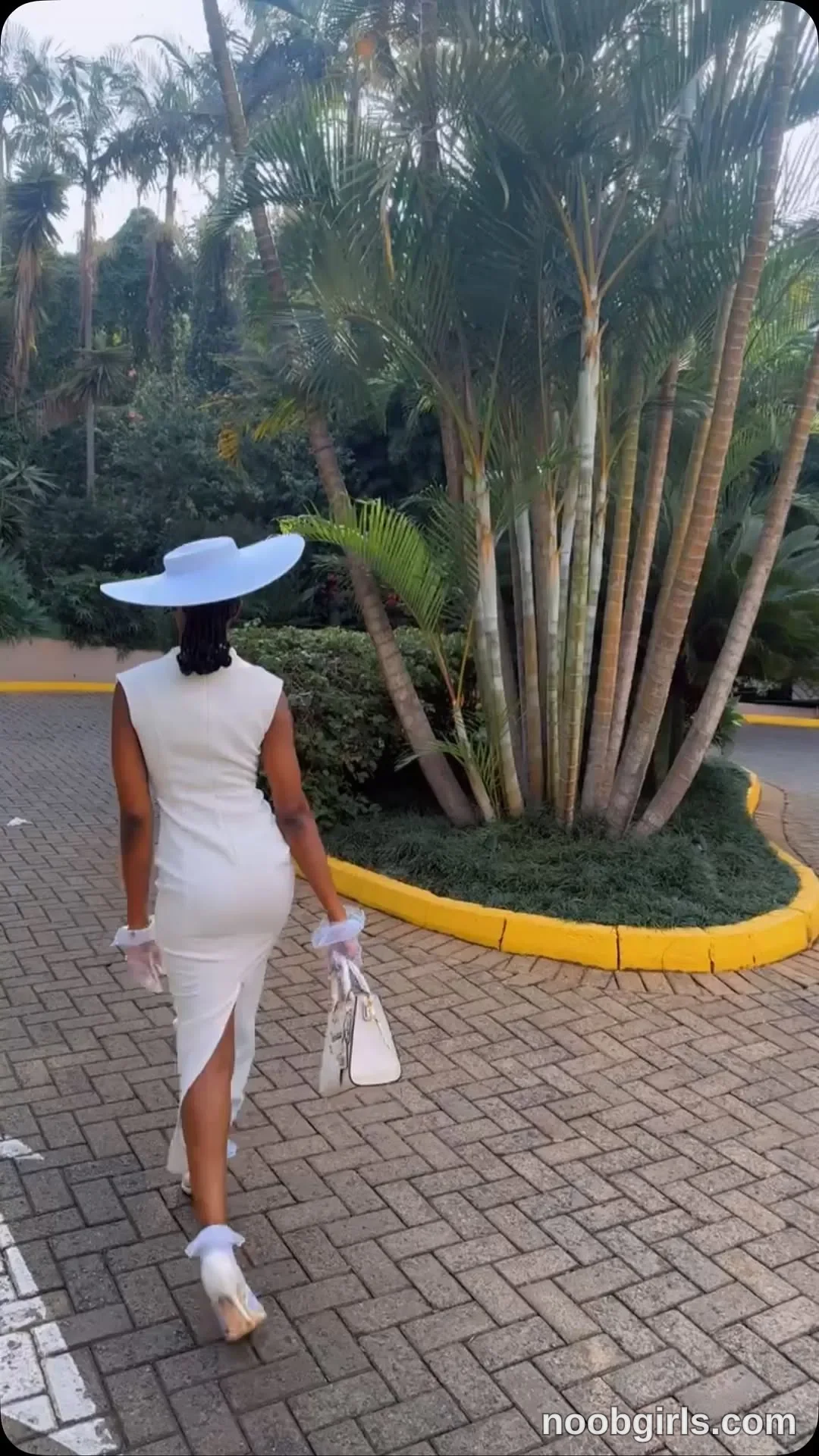 tootie03 Walking away from the camera wearing White sleeveless fitted midi dress with a back slit