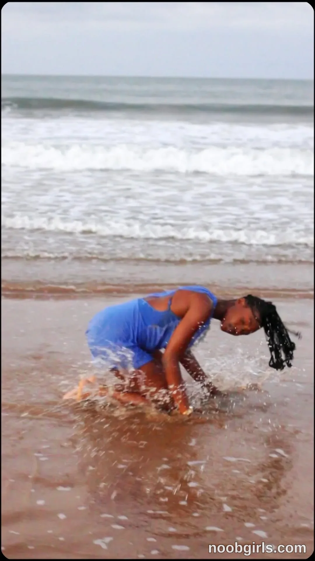 tootie03 Bending forward with knees bent wearing Blue sleeveless dress in beach