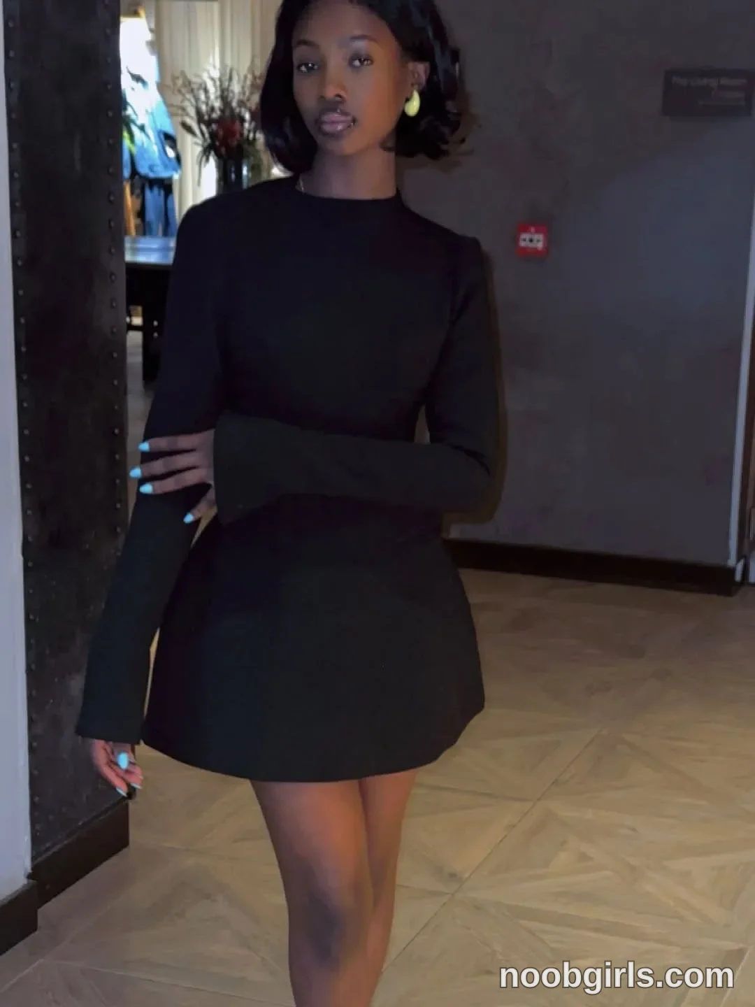 tootie03 Standing with one arm across her torso wearing Black long-sleeved mini dress with flared cuffs and a flared skirt