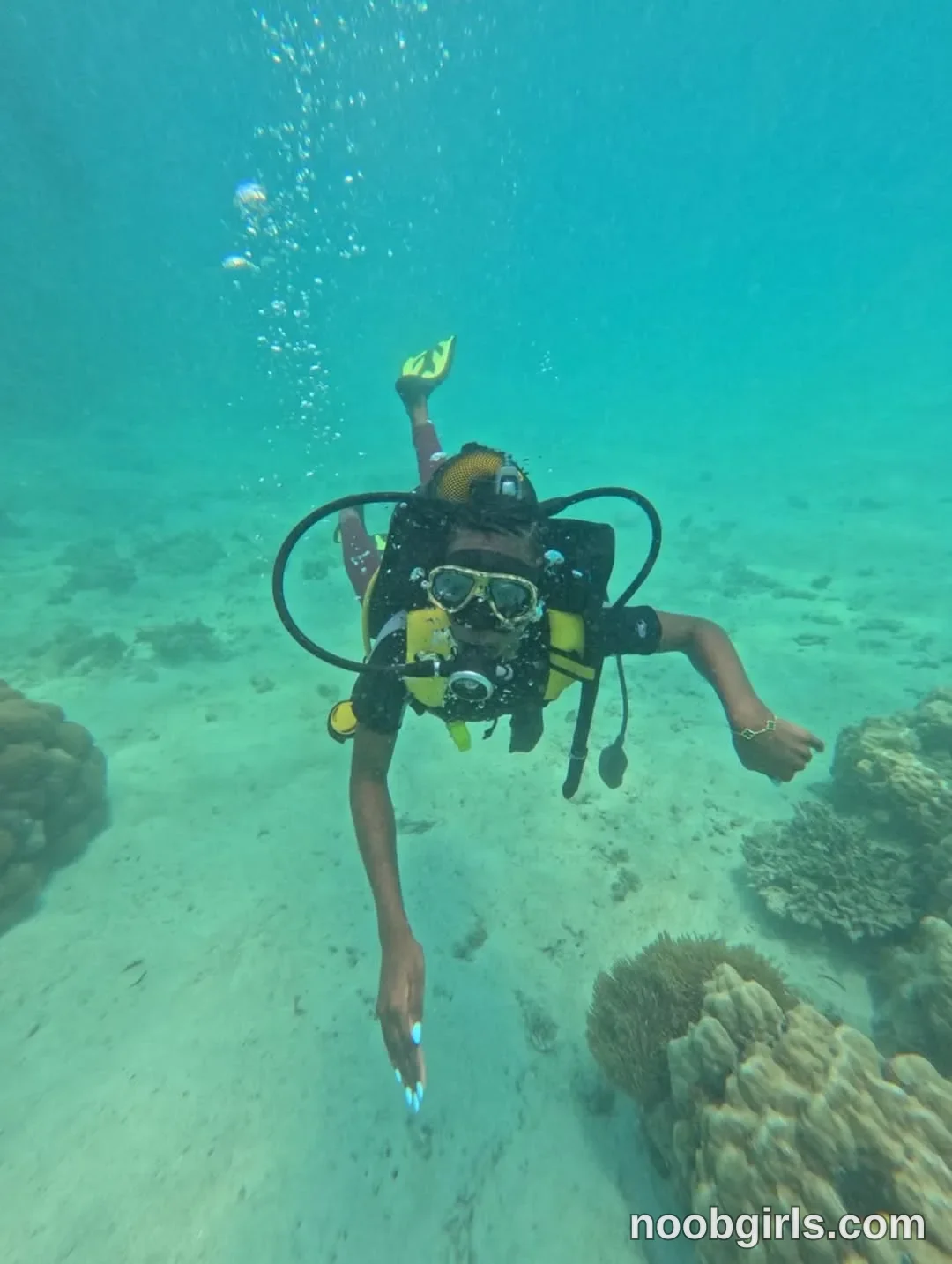 tootie03 swimming underwater with scuba equipment wearing dark short-sleeved swimwear in underwater above a sandy seabed
