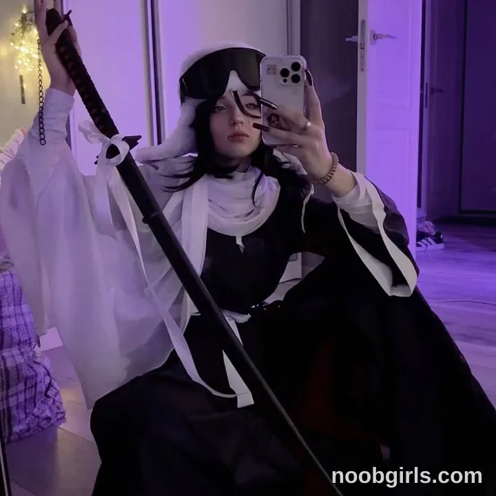 vivian_qwerty Posing with knees bent in front of a mirror wearing Black outfit with a white waist sash in room
