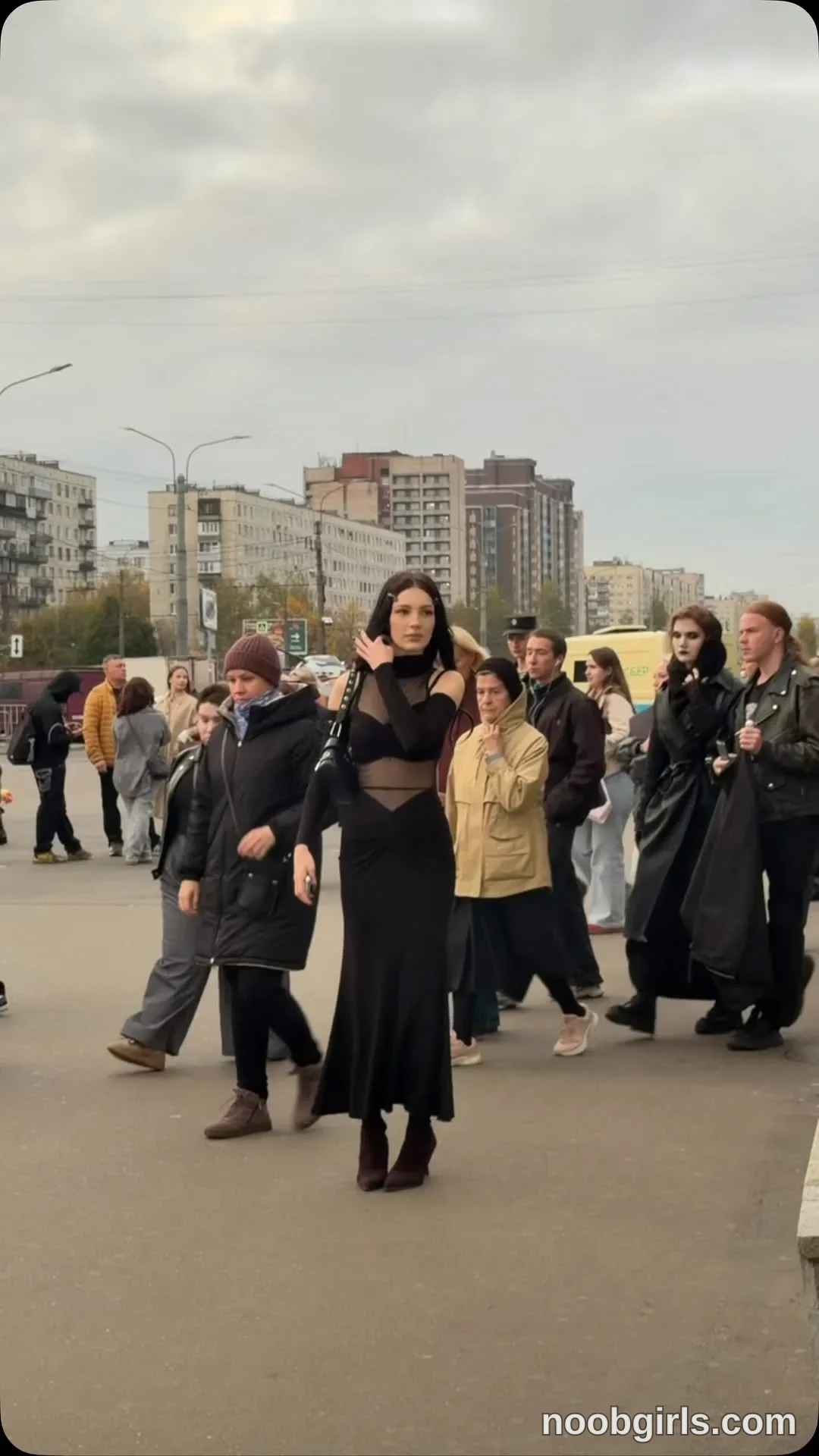 vivienne_northwood walking wearing black outfit with sheer sections in urban street or pedestrian area