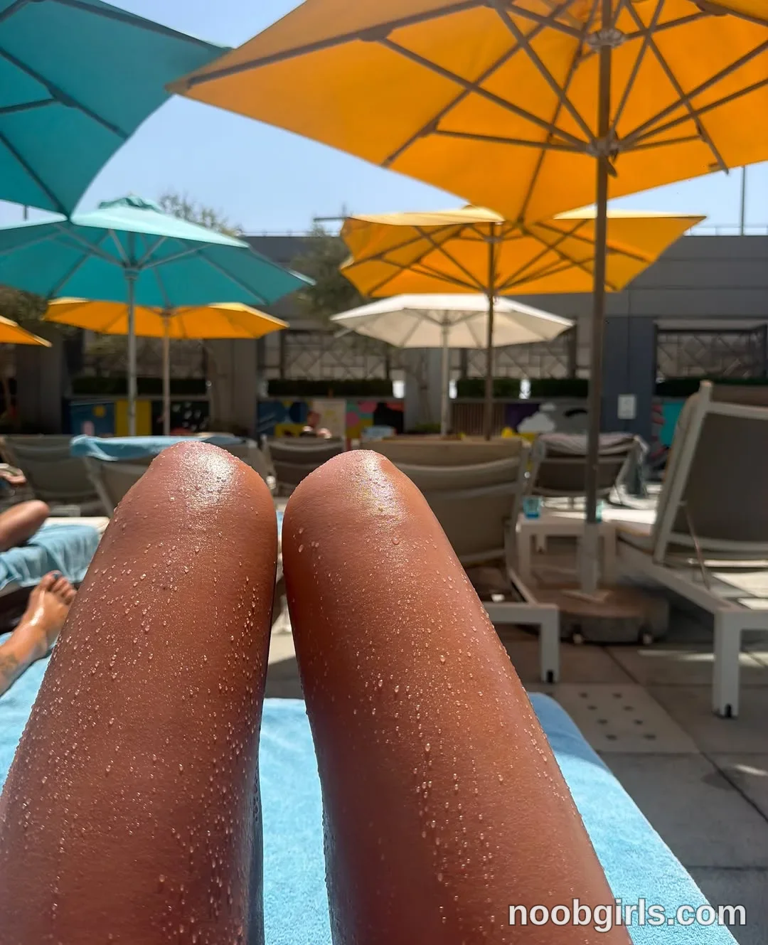 waki_lucky reclining on a blue-covered sun lounger with bare knees bent in sun-lounger area on a paved deck in Dubai