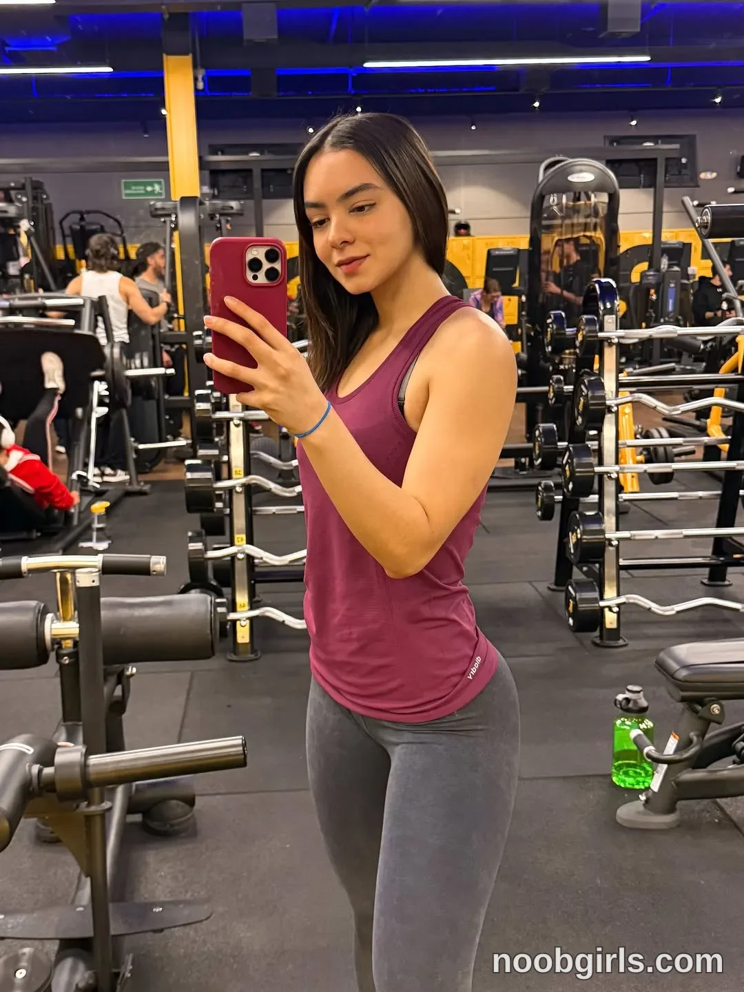 Wale taking a mirror selfie with a smartphone wearing sleeveless maroon/purple athletic tank top in gym / fitness centre
