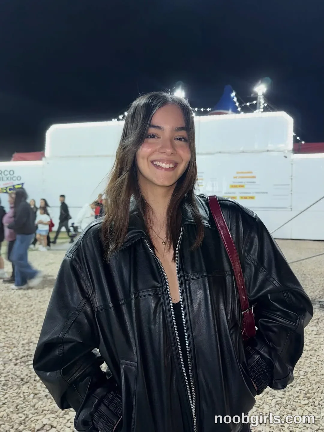 Wale wearing black leather oversized jacket with silver zippers in festival or fairground at night