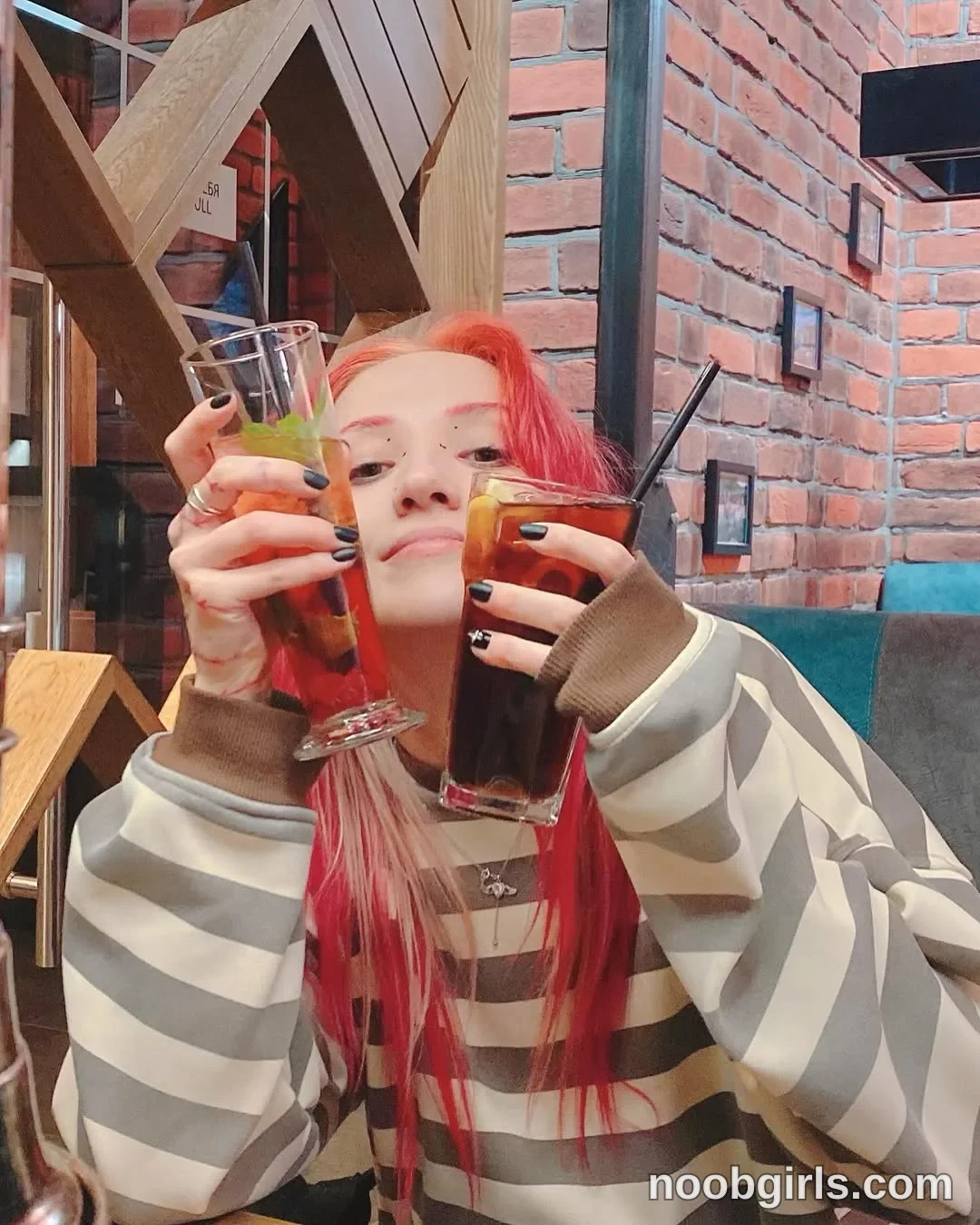 Lina Holding two drinks wearing gray-and-white horizontally striped long-sleeve top in restaurant or cafe