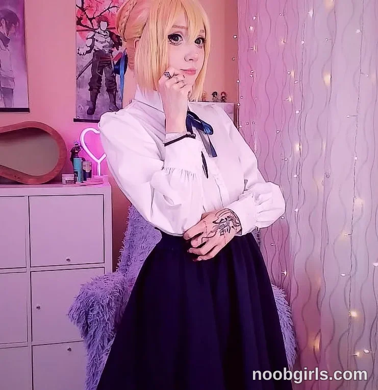 Lina Standing with one hand touching the cheek wearing white long-sleeved blouse in room